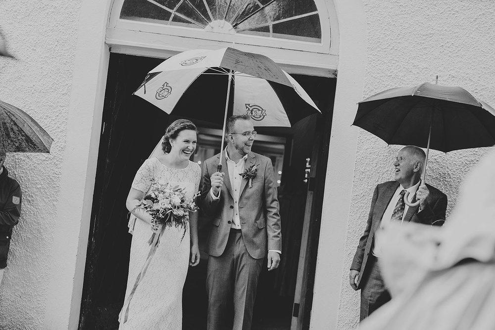 Brud i vit vintage spetsklänning och brudgum i grå kostym utanför kyrkan
