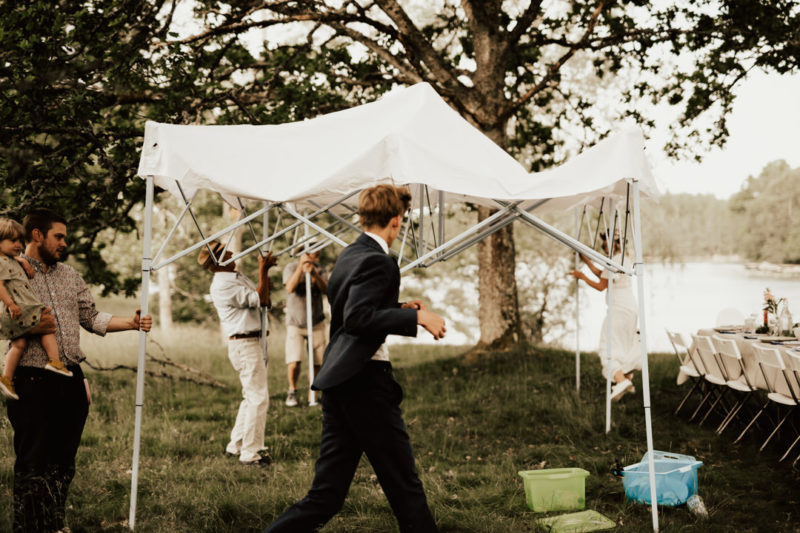 sätter upp tält vid regn till midsommarbröllop