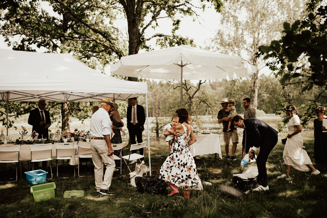 gäster och brudpar tar skydd under tält vid regn på midsommarbröllop
