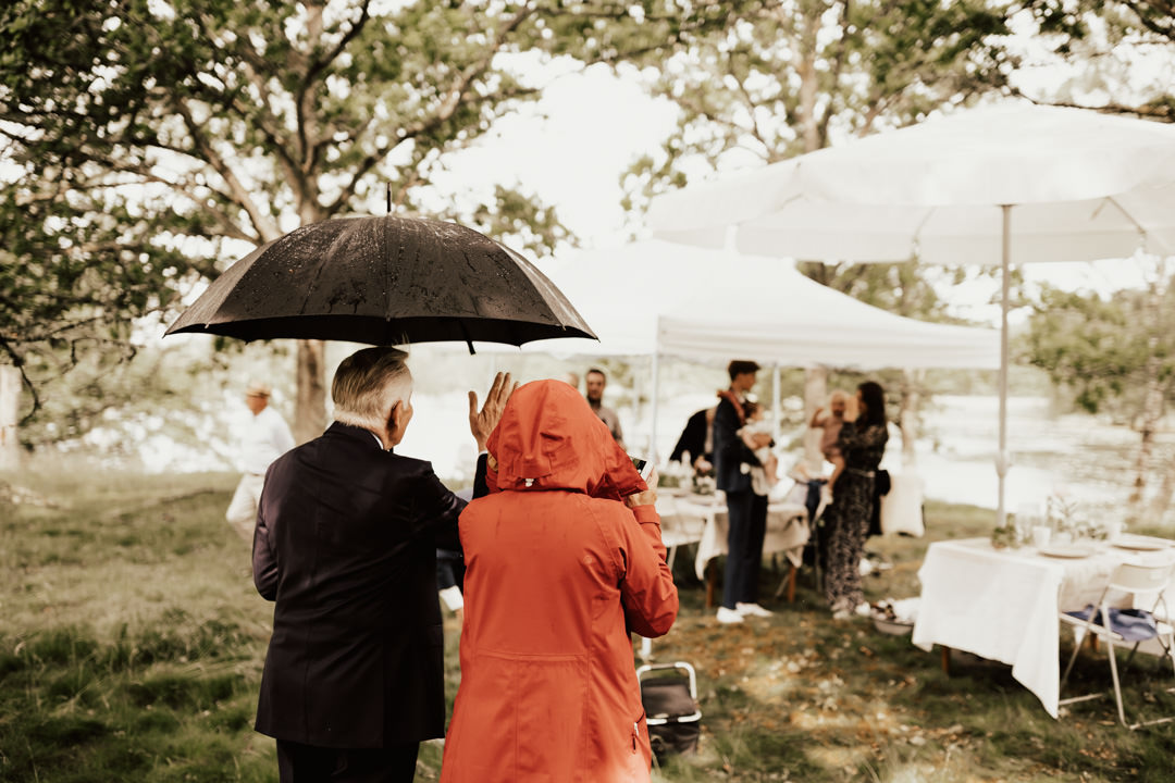 gäster står med paraply en bit ifrån på grund av corona