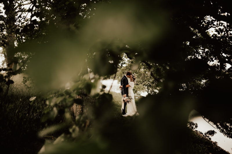 bohemiskt brudpar på midsommar under fotografering med fotograf i skog