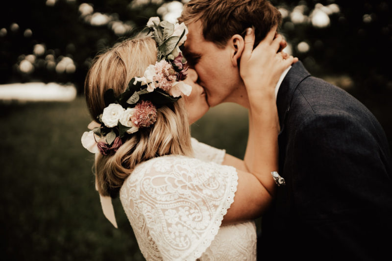 bohemiskt brudpar kysser varandra under porträttfotografering
