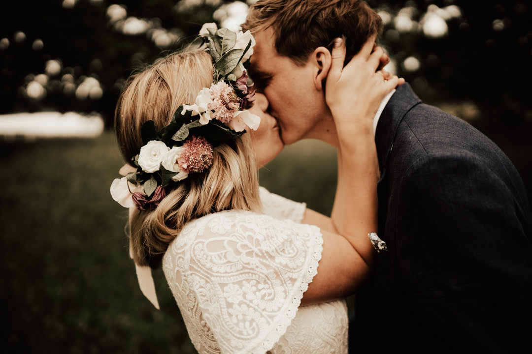 bohemiskt brudpar kysser varandra under porträttfotografering