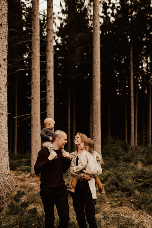 Familj med två barn i famnen busar under fotografering med Linnsej Photography
