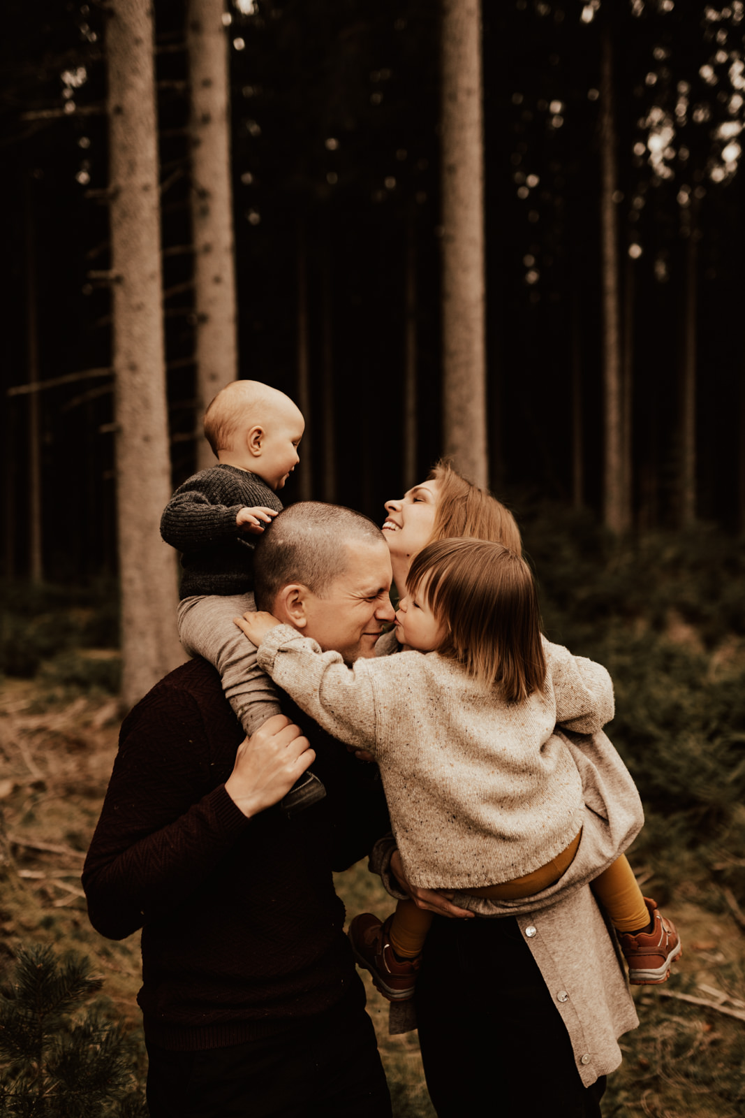 Familj med två barn i famnen busar under fotografering med Linnsej Photography