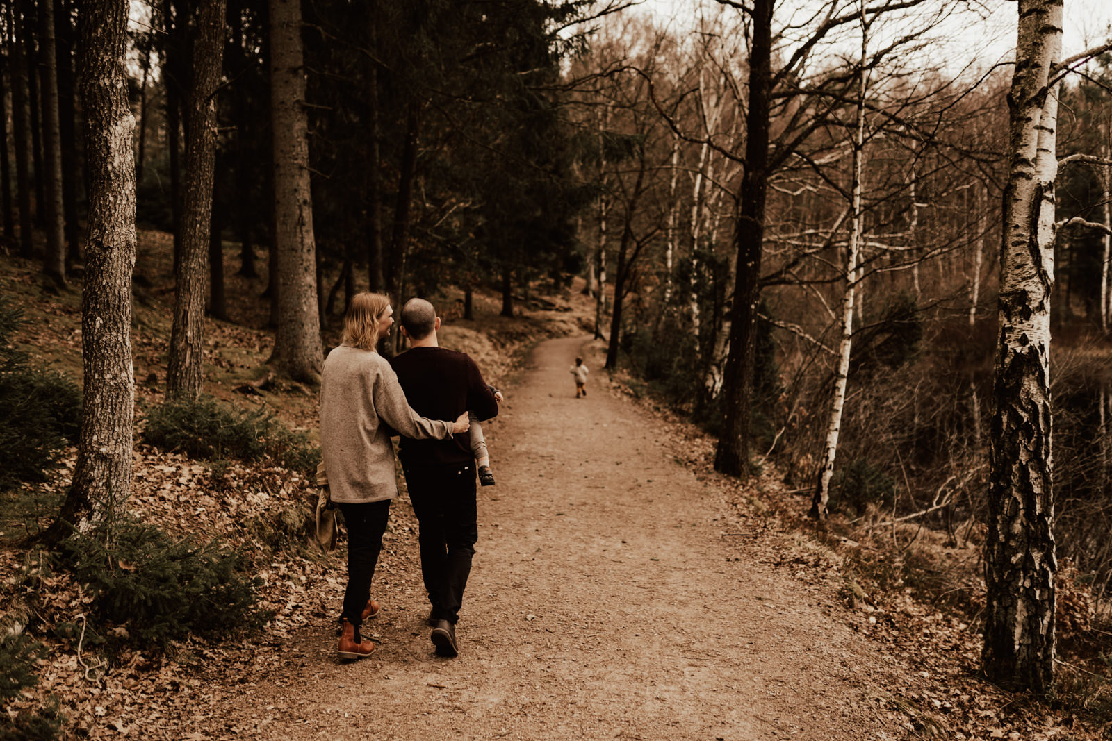 Familj går på stig i skog under familjefotografering i Halmstad