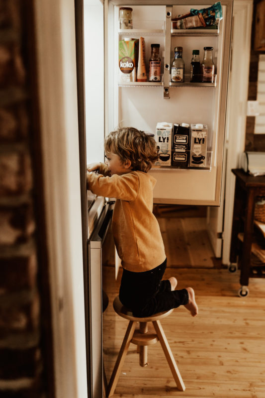 Barn klättar på pall vid kylskåp