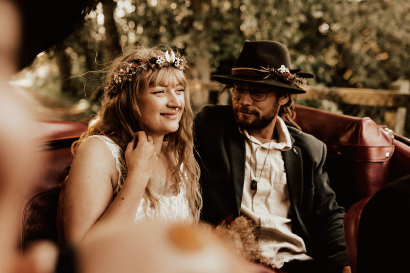 Boho wedding couple sits in the back of a retro car after the ceremony