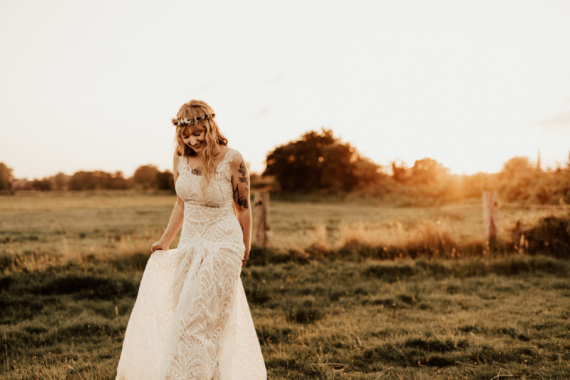 Bride walking in her bohemian lace dress during sunset photos at their boho festival wedding in Germany