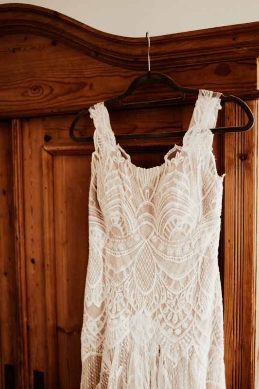 Boho wedding dress in lace hanging on wooden wardrobe