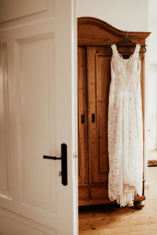 Bohemian wedding dress in lace hanging on wooden wardrobe