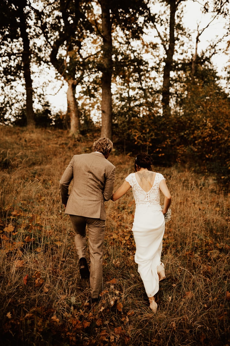 Brudpar går hand i hand i skogen i Sperlingsholm under deras bröllopsfotografering