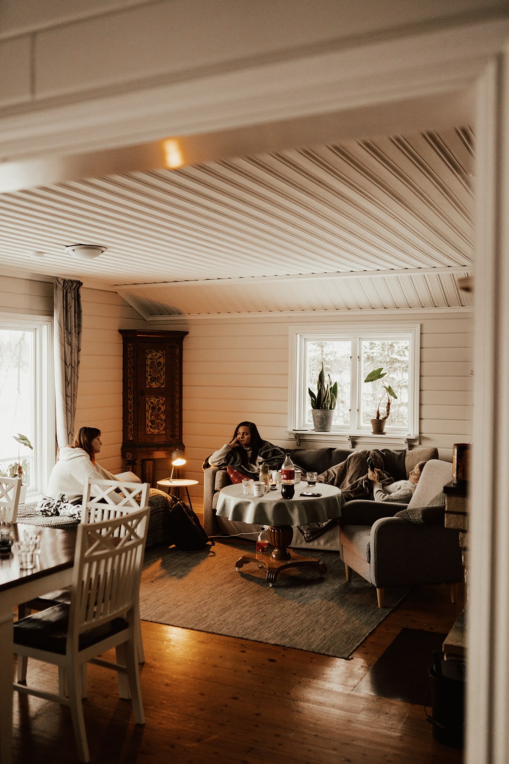 3 kvinnor sitter tillsammans i vardagsrum i en stuga med skandinavisk stil.
