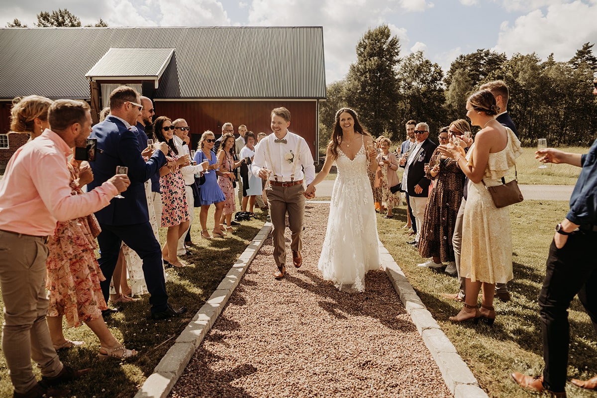 gäster på bröllop står på rad medan brudpar går igenom och skrattar.